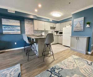 uma cozinha com paredes azuis e armários brancos e bancos de bar em Marylander Condominiums, 90 steps from the beach em Ocean City