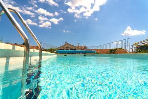 a swimming pool with blue water in front of a house at VILLA SALVIA - Holiday house with pool - in Jurdani