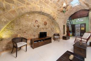 uma sala de estar com uma parede de pedra e uma televisão em Studio Astero in Ilha de Rhodes