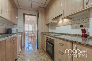 a large kitchen with wooden cabinets and appliances at Casa Bernat by MarCalma in Torredembarra
