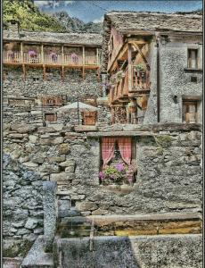 un edificio de piedra con balcón y sombrilla en La Baita Contemporanea; mix tra passato e presente, en Prato