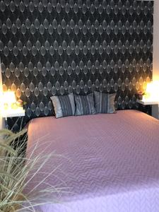 una camera con letto viola e testiera nera di Agnes Apartman a Latschach