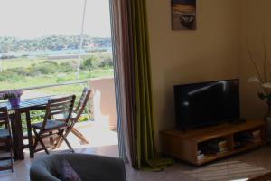a living room with a flat screen tv and a balcony at Helen's Sounio Apartments in Sounio