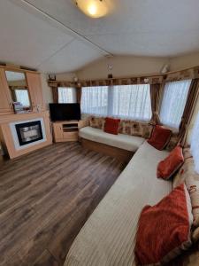 a living room with a bed and a tv and a couch at Pride caravan in Rhyl