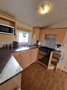 a kitchen with wooden cabinets and a stove top oven at Pride caravan in Rhyl