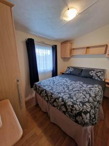 um quarto com uma cama e uma janela em Pride caravan em Rhyl