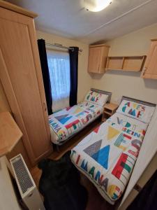 Habitación pequeña con 2 camas y ventana en Pride caravan en Rhyl