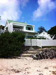 una casa sulla spiaggia con una recinzione bianca di Trou d’Eau Douce - Campement pieds dans l’eau a Trou d'Eau Douce