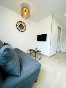 Sofá azul en la sala de estar con reloj en la pared en Studio cosy à Arcachon pour 2 personnes, en Arcachon