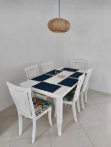 a white table with four white chairs and a basket at Trou d’Eau Douce - Campement pieds dans l’eau in Trou dʼ Eau Douce