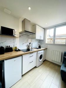 una cocina con gabinetes blancos y una lavadora y secadora en Studio cosy à Arcachon pour 2 personnes, en Arcachon