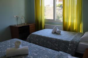 a room with two beds and a window with yellow curtains at Helen's Sounio Apartments in Sounio