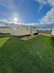 a mobile home in a yard with a grass field at Pride caravan in Rhyl