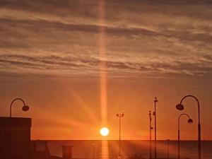 un coucher de soleil avec le soleil dans le ciel avec des lampadaires dans l'établissement T2 cosy à la plage, terrasse vue sur mer et parking privatif, à Narbonne