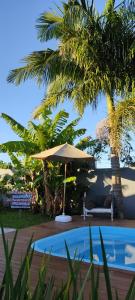 uma piscina com um guarda-sol ao lado de uma palmeira em Pousada Águas do Mampituba em Torres