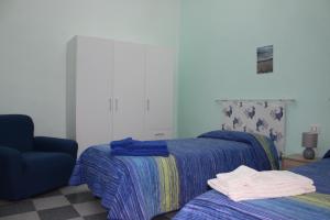 Casa Vacanze Nonna Franca في كابراس: غرفة نوم بسريرين وكرسي ازرق