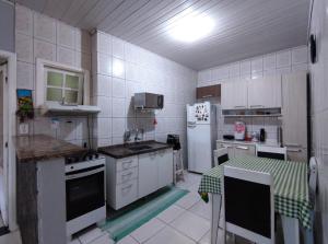 a kitchen with white appliances and a table in it at Casa individual aconchegante - Rio da praia - Bertioga in Bertioga