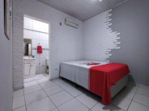 Habitación blanca con cama y baño. en Casa individual aconchegante - Rio da praia - Bertioga, en Bertioga
