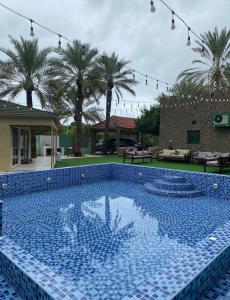 a large blue tile swimming pool in a yard with palm trees at Bedya Farm in Khor Fakkan