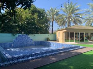 a swimming pool with blue tiles in a yard at Bedya Farm in Khor Fakkan