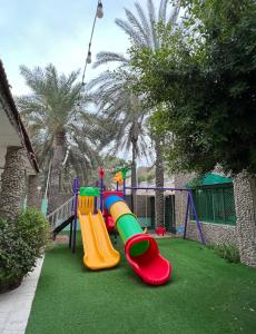 un parque infantil con un tobogán en el césped en Bedya Farm, en Khor Fakkan
