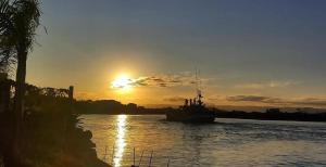 Pousada Águas do Mampituba في توريس: قارب على نهر مع غروب الشمس في الخلفية