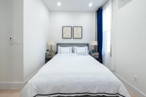ein weißes Schlafzimmer mit einem großen weißen Bett mit zwei Kissen in der Unterkunft 317-3D I NEW Modern 1BR W&D Walk to Central Park in New York