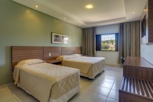 een hotelkamer met 2 bedden en een raam bij Hotel Fredy in Águas de Lindóia