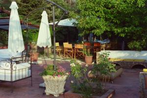 eine Terrasse mit Tischen, Sonnenschirmen und Blumen in Töpfen in der Unterkunft Villa Luxury nel Bosco in Castelbuono