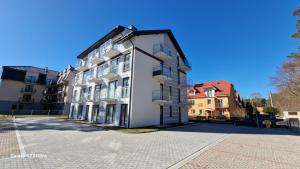 a white building on a street next to some buildings at Bursztynowe Międzywodzie in Międzywodzie