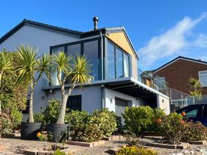 a house with glass windows and palm trees at Sea breeze Exmouth in Lympstone