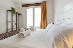 ein Schlafzimmer mit einem großen weißen Bett mit Handtüchern darauf in der Unterkunft Apartament Confort en Barri Port Maritim in Tarragona