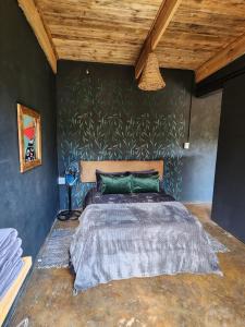 a bedroom with a bed with a green wall at Hartbeest eco bush lodge 2 in Hartbeespoort