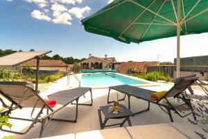 a pool with a table and chairs and a green umbrella at VILLA SALVIA - Holiday house with pool - in Jurdani