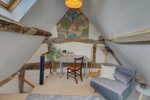 a attic room with a chair and a table at Loft Cottage by Spa Town Property - 2 Bed Tudor Retreat Near to Stratford-upon-Avon, Warwick & Solihull in Stratford-upon-Avon