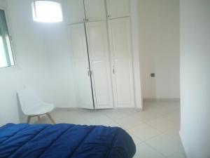 Akwaba lodge في ساليه: غرفة بيضاء بها سرير وكرسي وخزانة