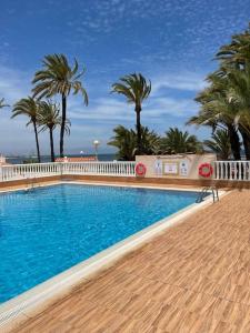 una piscina con palmeras y una valla blanca en VILLA MARE - 2 beds with balcony, patio and pool and direct park access, en Murcia