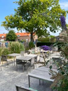 a patio with tables and chairs and a tree at Hotel Kijkduin in Domburg