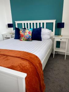 ein Bett mit einer orangefarbenen Decke und zwei Nachttischen in der Unterkunft Cairo House in Peacehaven