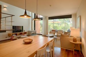 a living room with a wooden table and a dining room at Tróia Resort Beach Villa in Troia