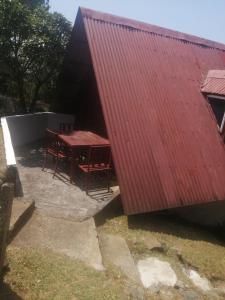 een rood overdekt gebouw met een tafel en stoelen ernaast bij Coffee Store La Cabaña in Valle Hornito