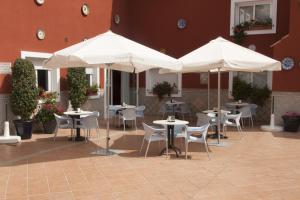 a patio with tables and chairs and umbrellas at Hotel Romerito in Málaga