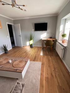 a living room with a table and a television on a wall at FineApartment Borgstedt in Borgstedt