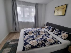 - un lit avec une couverture bleue et blanche et une fenêtre dans l'établissement New & Modern Apartment near Düsseldorf, à Willich