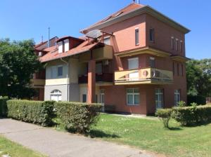 a large brick building with a balcony on a lawn at Solemio Apartman Kalocsa in Kalocsa