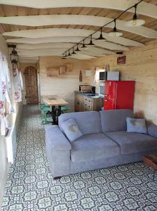 ein Wohnzimmer mit einem Sofa und einer Küche in der Unterkunft Ma roulotte adorée in Bissières