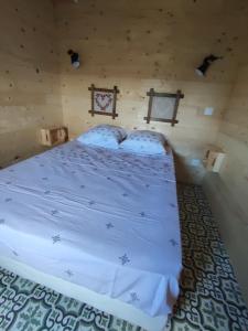ein Schlafzimmer mit einem Bett in einem Blockhaus in der Unterkunft Ma roulotte adorée in Bissières