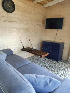 Zimmer mit Sofa, TV und Tisch in der Unterkunft Ma roulotte adorée in Bissières