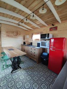 eine Küche mit einem roten Kühlschrank und einem Tisch in der Unterkunft Ma roulotte adorée in Bissières
