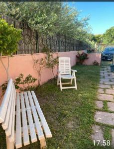 dos sillas y un banco junto a una valla en Casa rossa, en Solanas